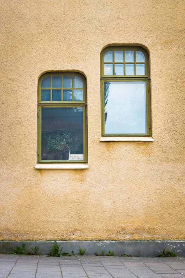 two windows on a yellow wall